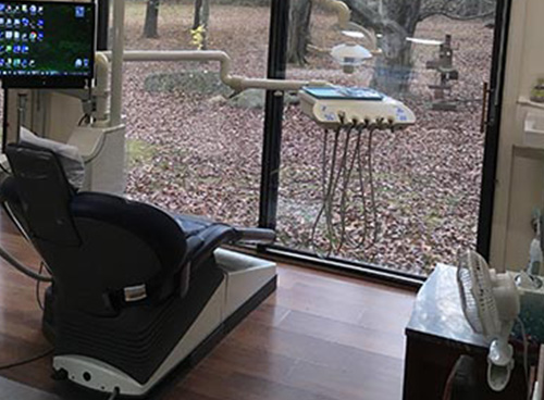 The image shows a dental office interior with a dental chair and equipment visible through a window.