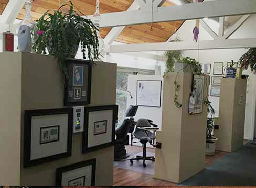 An interior office space with a high ceiling, exposed beams, and a mix of furniture and decorations.